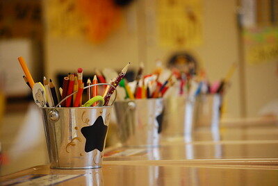 Small silver buckets decorated with black stars are filled with pencils and other school supplies.